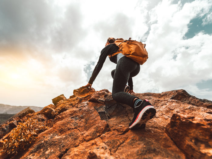 Woman climbing to the peak of the mountain