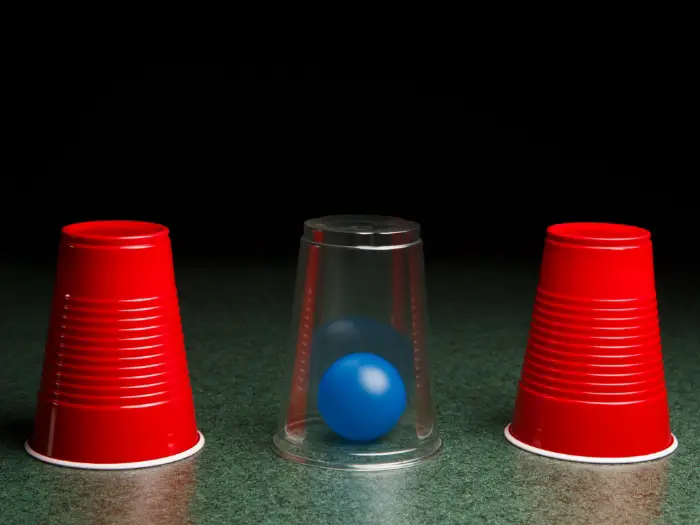 Showing the guess which ball is in one of the 3 cups. One cup is clear and has the ball in it - with the analogy that UWorld is the easy choice to make for CFA prep.